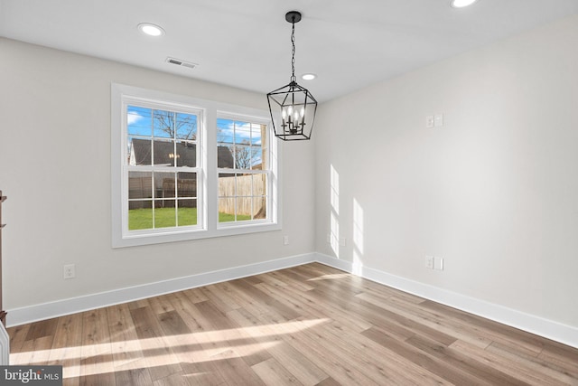 unfurnished dining area featuring light hardwood / wood-style floors and a notable chandelier