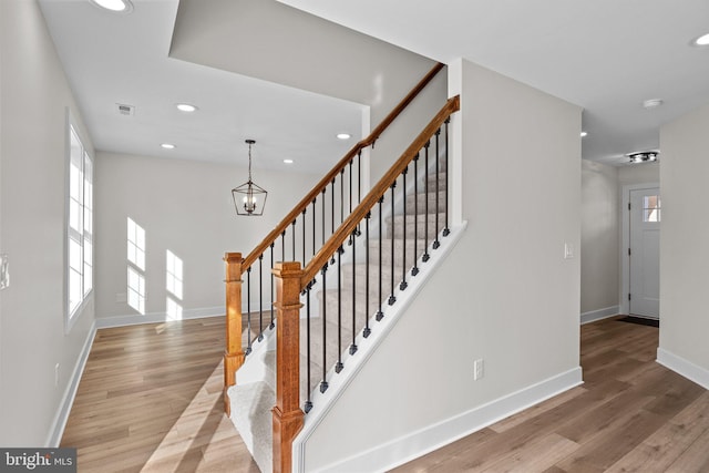 stairway featuring hardwood / wood-style flooring and a notable chandelier