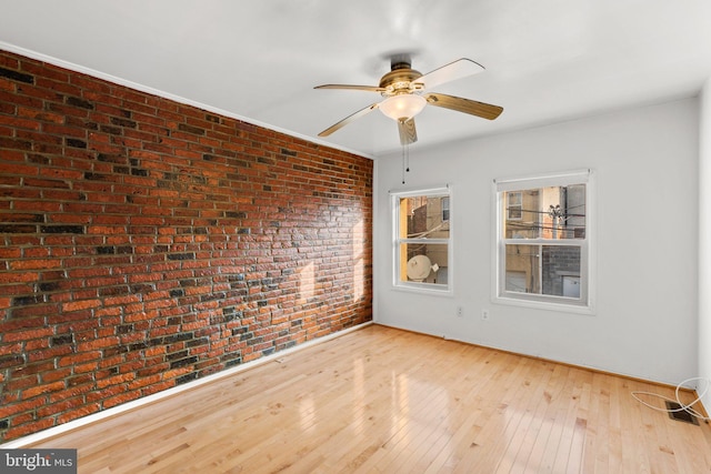 unfurnished room featuring light hardwood / wood-style flooring and brick wall