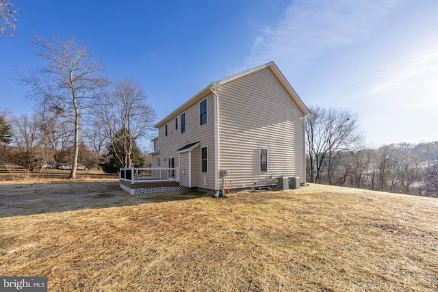 view of side of property with a yard, central air condition unit, and a wooden deck