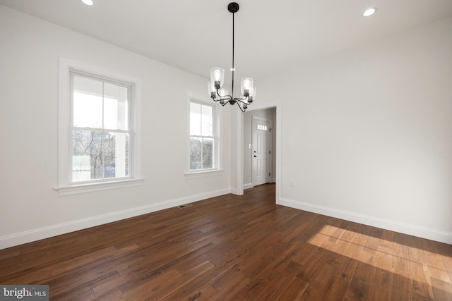 unfurnished dining area featuring dark wood-type flooring and a notable chandelier