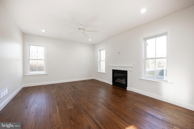 unfurnished living room featuring ceiling fan, plenty of natural light, and dark wood-type flooring