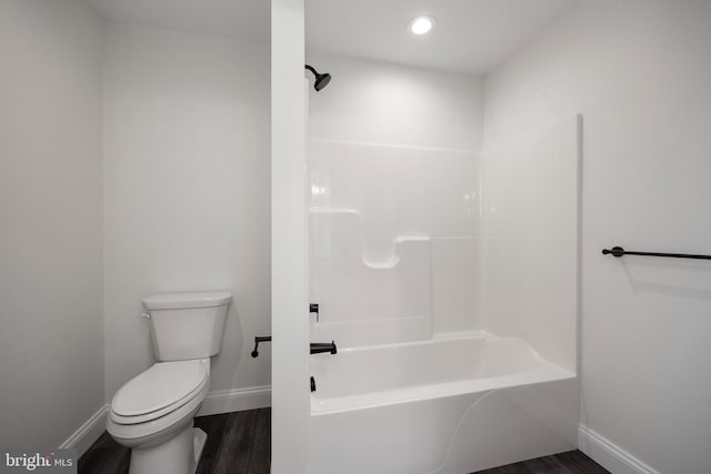 bathroom featuring hardwood / wood-style flooring,  shower combination, and toilet