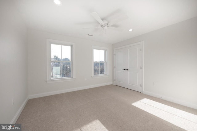 spare room with ceiling fan and light carpet