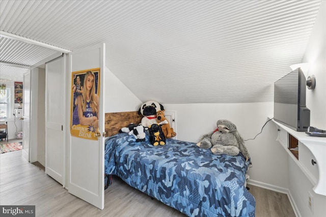 bedroom with vaulted ceiling and light hardwood / wood-style flooring