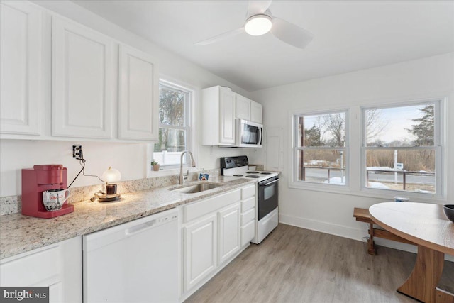 kitchen featuring sink, white cabinetry, light stone counters, light wood-type flooring, and white appliances