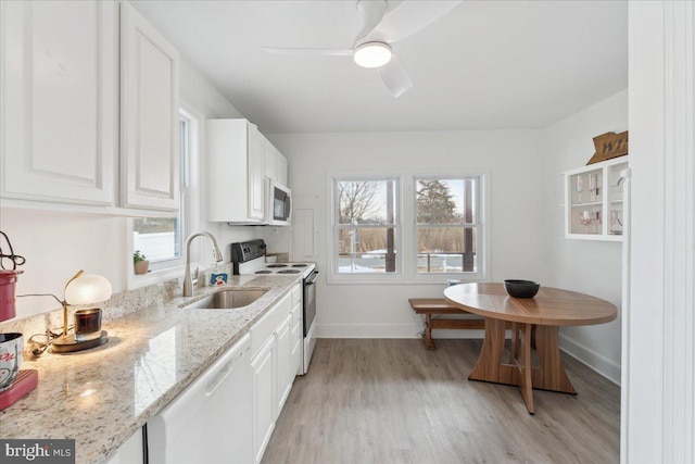 kitchen with sink, white cabinetry, white appliances, light stone countertops, and light hardwood / wood-style floors