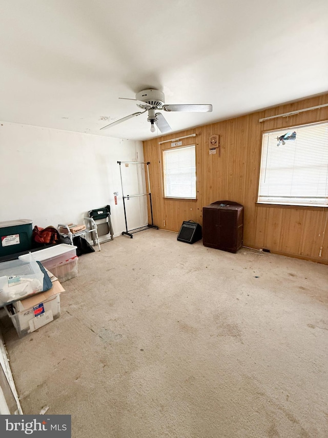 interior space featuring ceiling fan, plenty of natural light, and wood walls