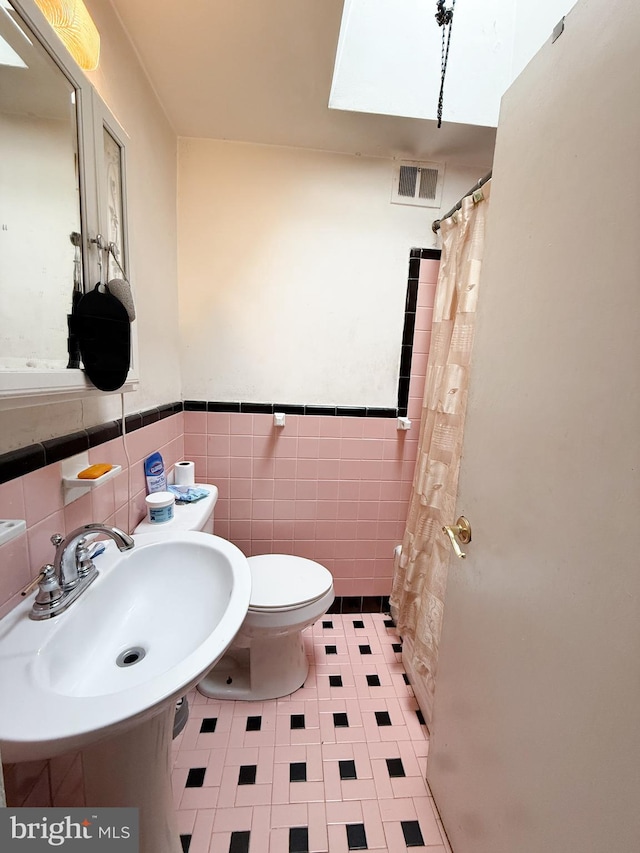 bathroom with sink, tile walls, and toilet