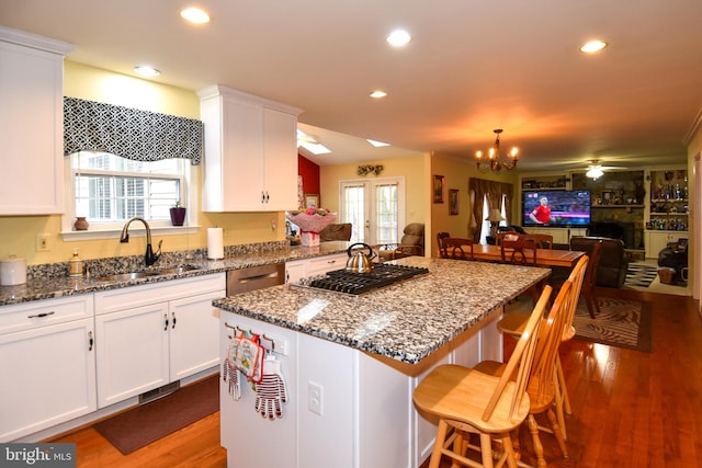 kitchen featuring sink, a kitchen island, a breakfast bar, white cabinets, and hardwood / wood-style flooring