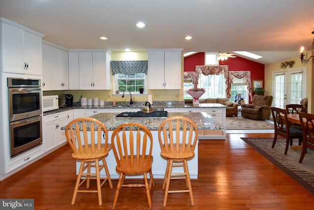 kitchen with a center island, lofted ceiling, appliances with stainless steel finishes, dark hardwood / wood-style flooring, and a breakfast bar area