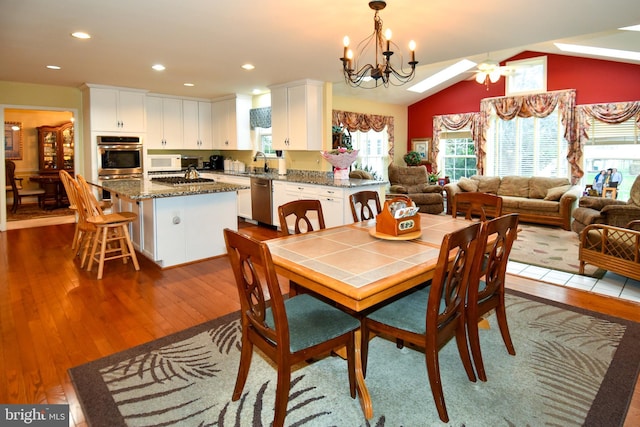 dining room with dark hardwood / wood-style floors, sink, lofted ceiling, and ceiling fan with notable chandelier