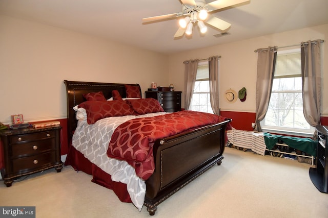 carpeted bedroom with multiple windows and ceiling fan