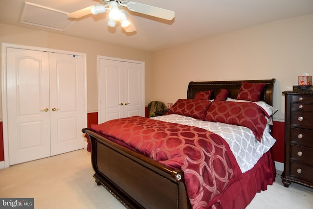 carpeted bedroom featuring ceiling fan and two closets