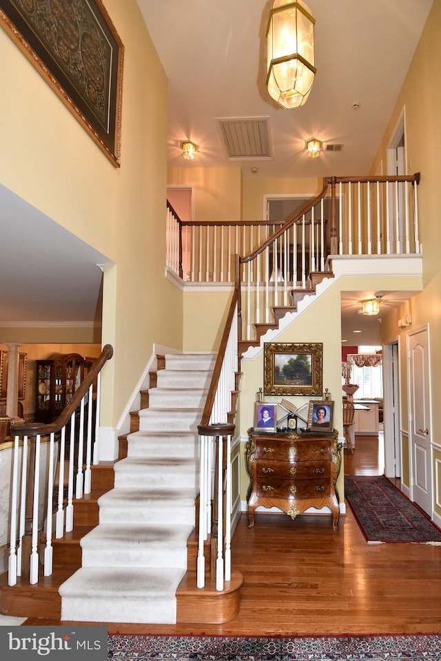 staircase featuring hardwood / wood-style floors and a towering ceiling