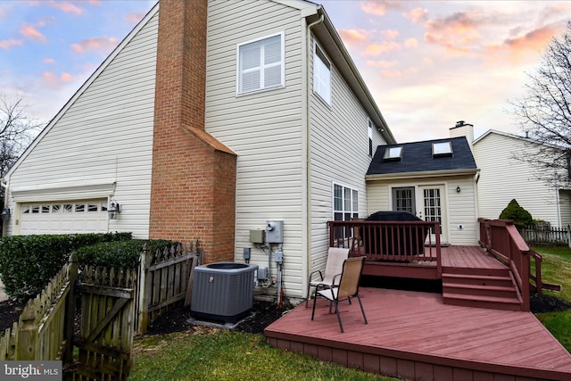 back house at dusk with central AC unit and a wooden deck