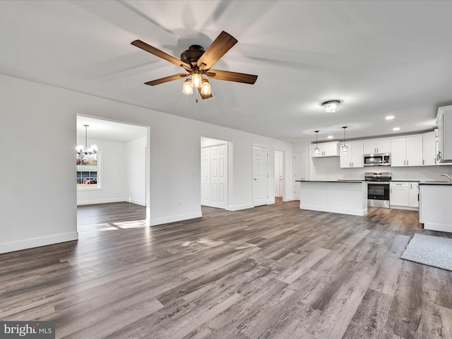 unfurnished living room featuring ceiling fan with notable chandelier, wood-type flooring, and sink