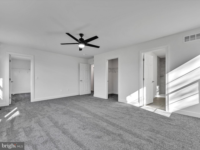 unfurnished bedroom featuring a spacious closet, a closet, ceiling fan, and light carpet