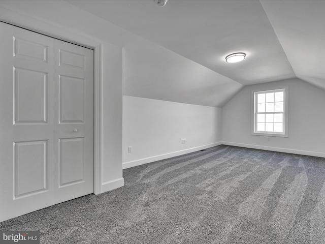 bonus room with lofted ceiling and dark colored carpet