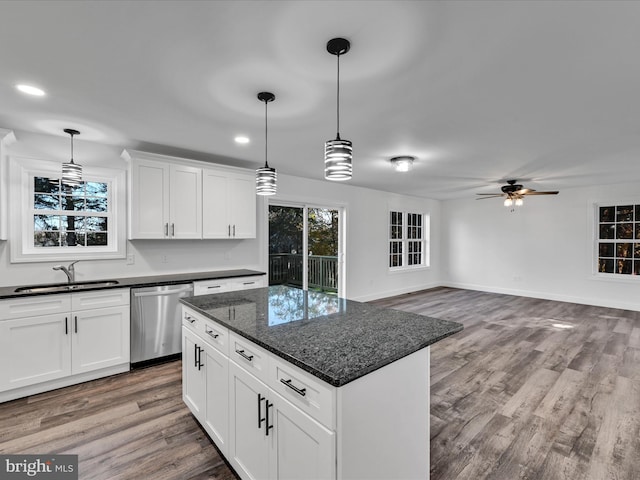 kitchen featuring white cabinetry, dishwasher, dark stone counters, and light wood-type flooring