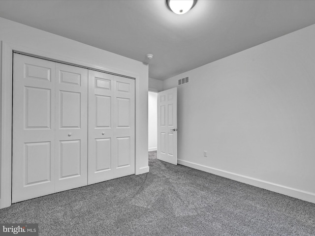 unfurnished bedroom featuring dark carpet and a closet