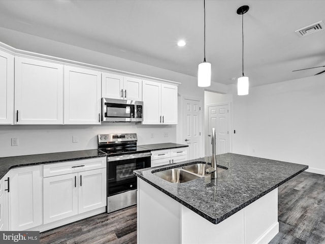 kitchen with white cabinets, dark hardwood / wood-style flooring, stainless steel appliances, and an island with sink