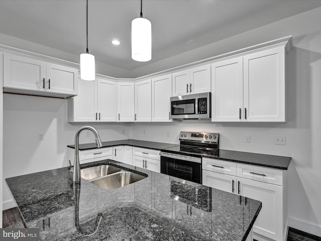 kitchen with dark stone counters, white cabinets, sink, hanging light fixtures, and stainless steel appliances