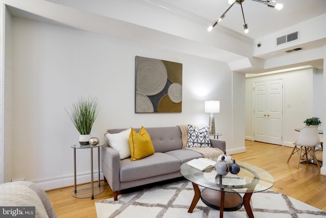 living room featuring visible vents, crown molding, and wood finished floors