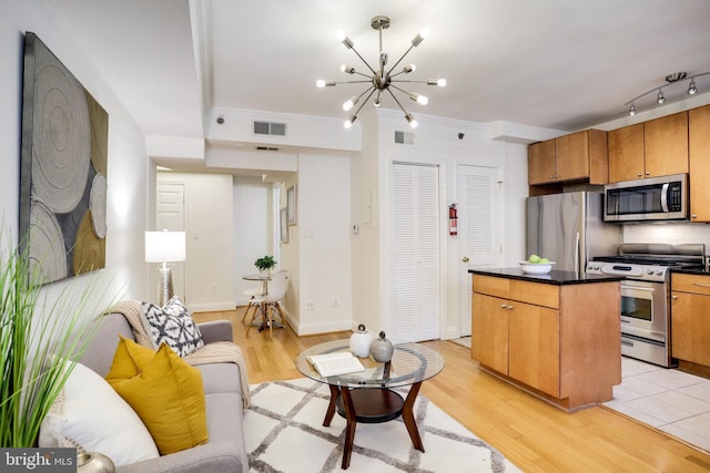 kitchen with a center island, visible vents, appliances with stainless steel finishes, brown cabinets, and dark countertops