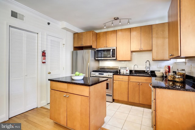 kitchen with visible vents, dark stone counters, a kitchen island, appliances with stainless steel finishes, and a sink