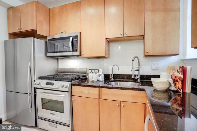 kitchen with dark stone counters, stainless steel appliances, tasteful backsplash, and a sink