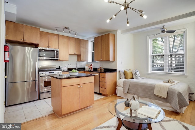 kitchen featuring dark countertops, appliances with stainless steel finishes, open floor plan, a center island, and backsplash