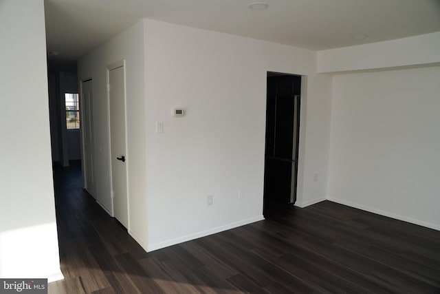 unfurnished room with dark hardwood / wood-style flooring