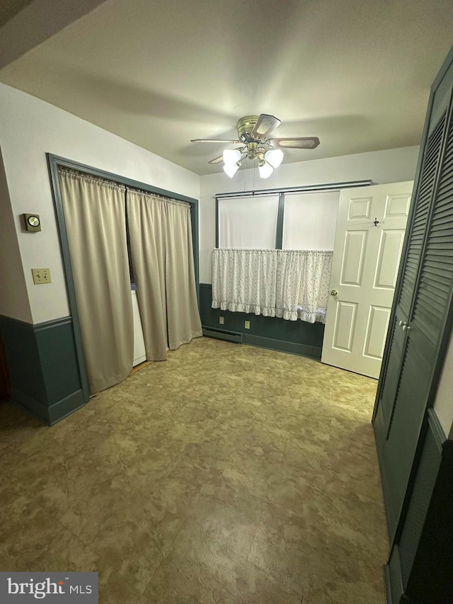 unfurnished bedroom featuring ceiling fan and a baseboard heating unit