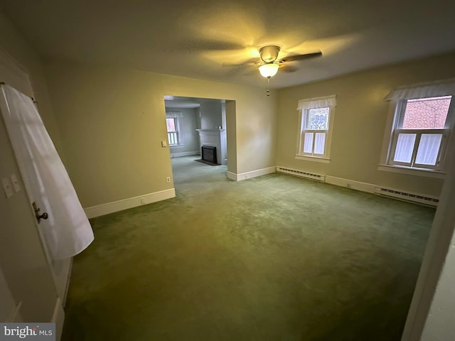 carpeted spare room with a baseboard radiator and ceiling fan