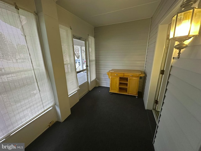 corridor featuring dark colored carpet and crown molding