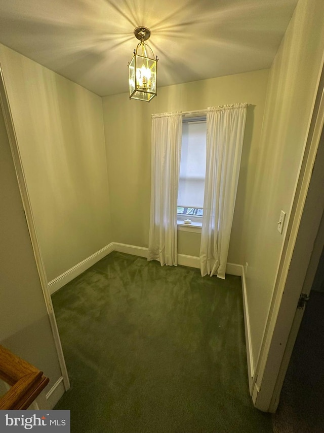 carpeted empty room with an inviting chandelier