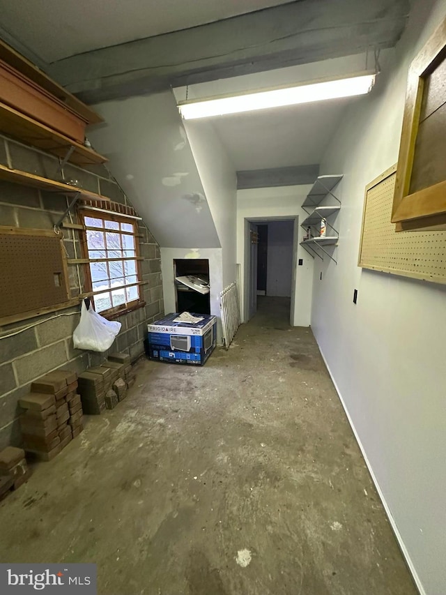 corridor featuring lofted ceiling and concrete floors