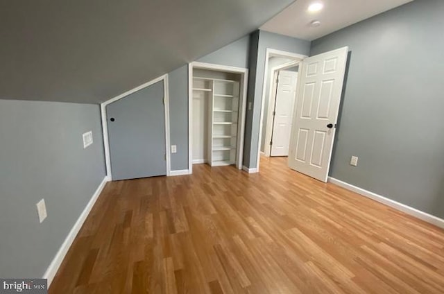 additional living space with light hardwood / wood-style floors and vaulted ceiling