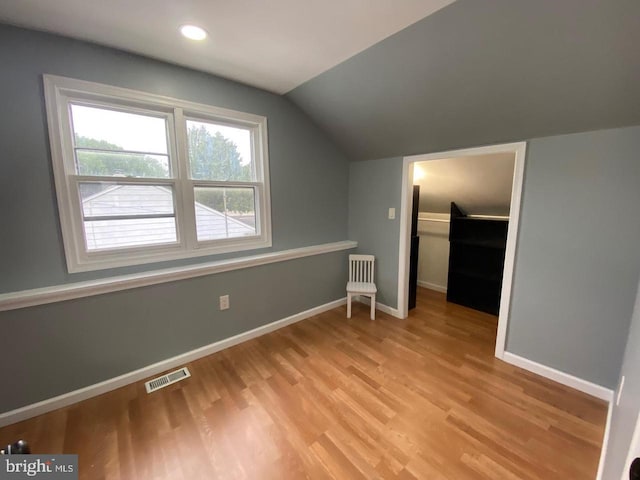 additional living space featuring lofted ceiling and light wood-type flooring