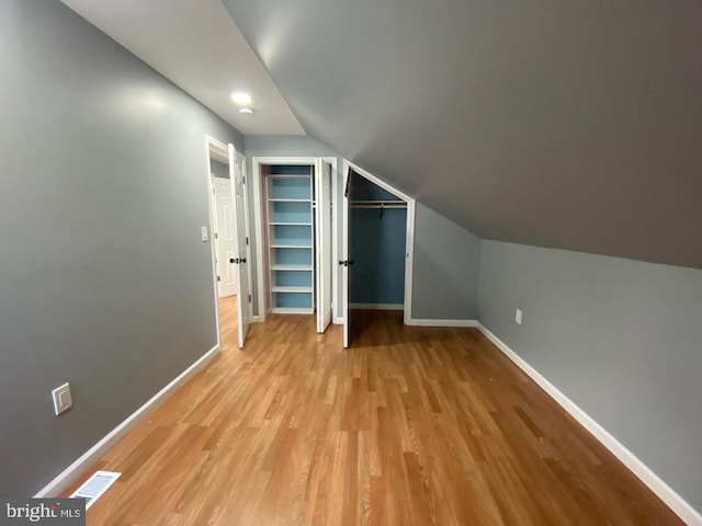 additional living space with lofted ceiling and light hardwood / wood-style flooring