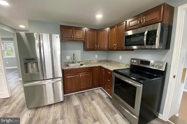 kitchen featuring light stone countertops, stainless steel appliances, hardwood / wood-style flooring, and sink