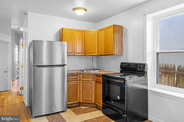 kitchen with stainless steel fridge, light wood-type flooring, sink, and black / electric stove