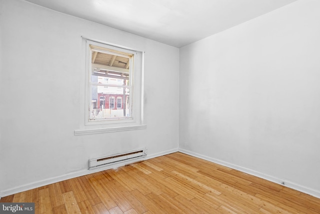 spare room featuring a baseboard radiator and hardwood / wood-style flooring