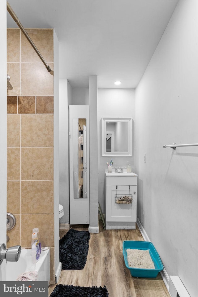 bathroom featuring toilet, vanity, a baseboard radiator, and hardwood / wood-style flooring