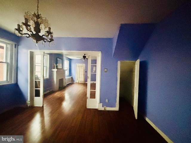 interior space featuring dark hardwood / wood-style floors, a healthy amount of sunlight, radiator heating unit, and ceiling fan with notable chandelier