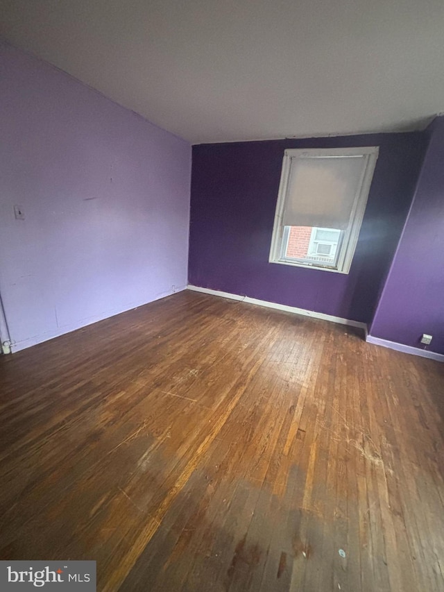 unfurnished room featuring dark hardwood / wood-style floors and vaulted ceiling