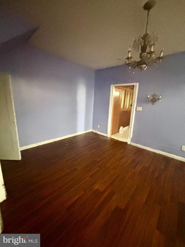 empty room with hardwood / wood-style floors and a notable chandelier