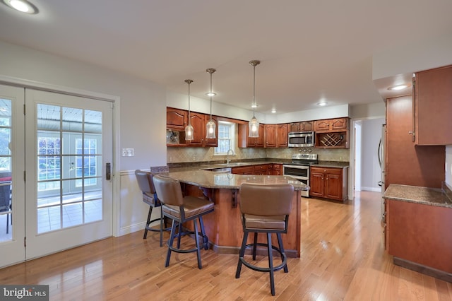 kitchen featuring kitchen peninsula, appliances with stainless steel finishes, light hardwood / wood-style flooring, and a healthy amount of sunlight