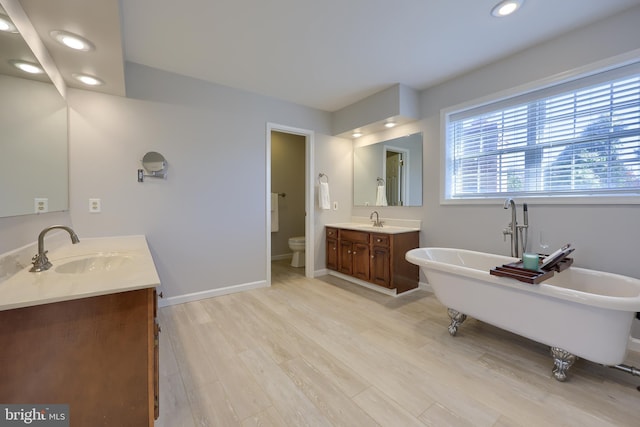 bathroom featuring a washtub, vanity, hardwood / wood-style flooring, and toilet